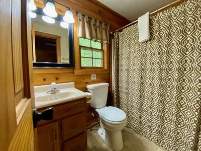 a bathroom with a toilet and a sink and a mirror at Pine Creek - by The Chalets in South Bloomingville
