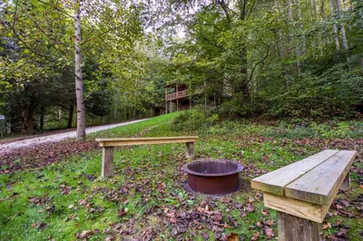 a wooden bench and a fire pit in a park at Pioneer - by The Chalets in South Bloomingville