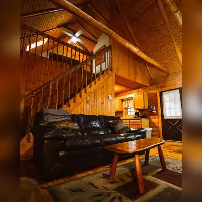 a living room with a black leather couch and a table at Pioneer - by The Chalets in South Bloomingville