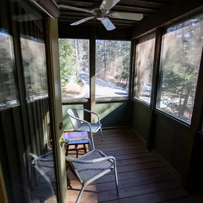 a screened in porch with two chairs and a ceiling fan at Ravine - by The Chalets in Logan