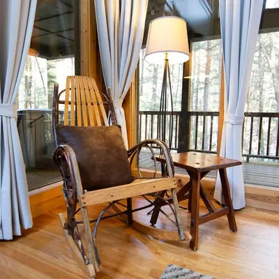 a rocking chair and a table in a room with windows at Ravine - by The Chalets in Logan