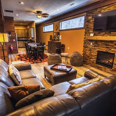 a living room with a leather couch and a fireplace at Rockhouse - by The Chalets in Logan