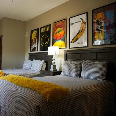 two beds in a room with posters on the wall at Rockhouse - by The Chalets in Logan