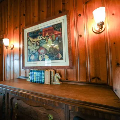 a painting on a wall above a wooden table with books at Settler - by The Chalets in Logan