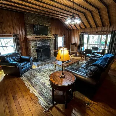 a living room with leather furniture and a stone fireplace at Settler - by The Chalets in Logan