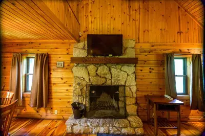 a living room with a fireplace in a log cabin at Sycamore - by The Chalets in South Bloomingville