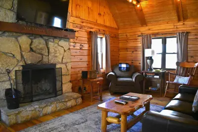 a living room with a stone fireplace in a cabin at Sycamore - by The Chalets in South Bloomingville