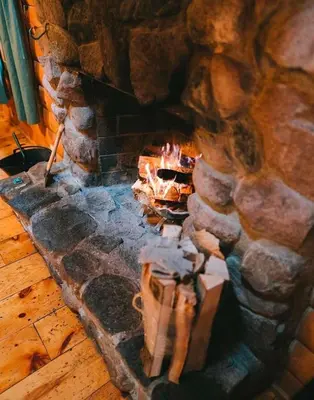 a stone fireplace with a fire in it at Sycamore - by The Chalets in South Bloomingville
