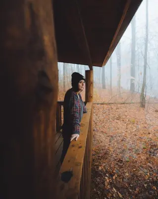 a woman standing on a fence in a cabin at Timber Ridge - by The Chalets in South Bloomingville