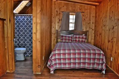 a bedroom with a bed and a window and a toilet at Timber Ridge - by The Chalets in South Bloomingville