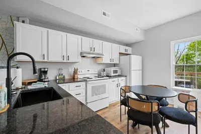 a kitchen with white cabinets and a table with chairs at 2BR Condo Near Ark for 6 Guests - Free Parking in Williamstown