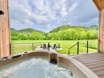 a hot tub on a deck with a view of a field at Hiker's Haven at Three Suns Cabins in Stanton