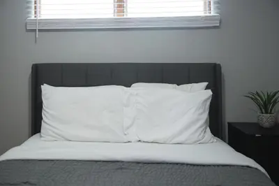 a bedroom with a bed with white pillows and a window at The Halftime Highlight-Big Plays, Comfy Stays in Canton