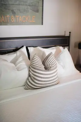 a pillow sitting on a bed with white pillows at Getaway Inn at Cooper's Woods in Put-in-Bay