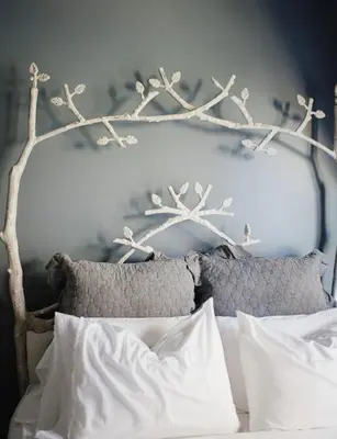 a bed with a white headboard with branches on it at Getaway Inn at Cooper's Woods in Put-in-Bay