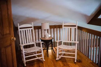 a room with two rocking chairs and a table with a lamp at Getaway Inn at Cooper's Woods in Put-in-Bay