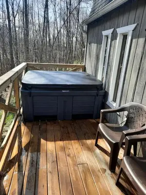 a hot tub sitting on a deck with a chair at Secluded Cabin Rental, Perfect for an Ohio Retreat in Scio