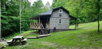 a house on a hill with a picnic table and a bench at Secluded Cabin Rental, Perfect for an Ohio Retreat in Scio