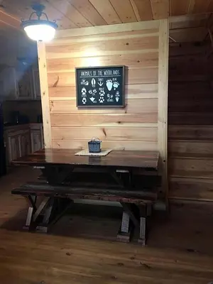 a wooden table in a cabin with a sign on the wall at Authentic Stunning Cabin Rental with Private Jacuzzi near Huntington, West Virginia in Genoa