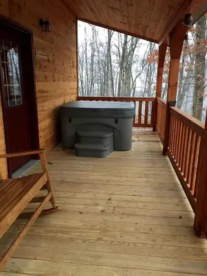 a wooden porch with a bath tub in a cabin at Authentic Stunning Cabin Rental with Private Jacuzzi near Huntington, West Virginia in Genoa