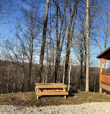 a wooden picnic table sitting next to a cabin at Authentic Stunning Cabin Rental with Private Jacuzzi near Huntington, West Virginia in Genoa