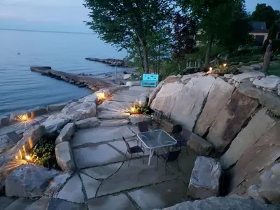 a patio with lights next to the water at night at Charming Beach Cottage Along Lake Erie near Cleveland, Ohio in Vermilion