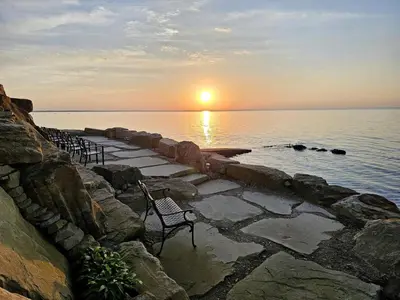 a row of chairs sitting on a stone path near the water at Charming Beach Cottage Along Lake Erie near Cleveland, Ohio in Vermilion