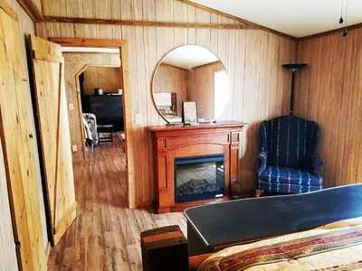 a bedroom with a fireplace and a chair and a mirror at Gorgeous Family-Friendly Cabin with Fire Pit near Huntington, West Virginia in Genoa