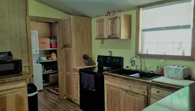 a kitchen with wooden cabinets and a black refrigerator at Gorgeous Family-Friendly Cabin with Fire Pit near Huntington, West Virginia in Genoa