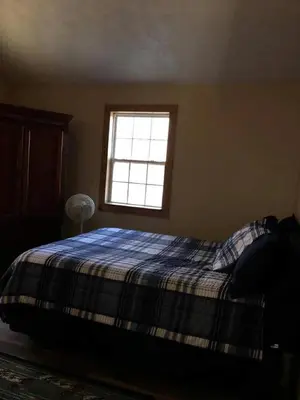 a bedroom with a bed with a plaid blanket and a window at Stunning Getaway Cabin with Expansive Decks near Huntington, West Virginia in Genoa