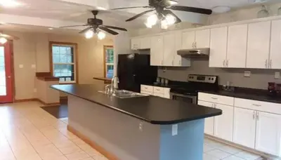 a kitchen with white cabinets and a black counter top at Stunning Getaway Cabin with Expansive Decks near Huntington, West Virginia in Genoa