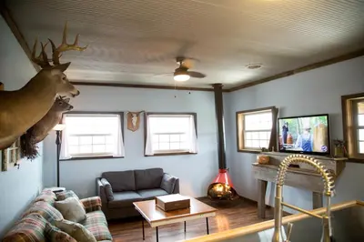 a living room with a couch and a deer head on the wall at Rustic Cabin in the Countryside near Muskingum River State Park, Ohio in McConnelsville