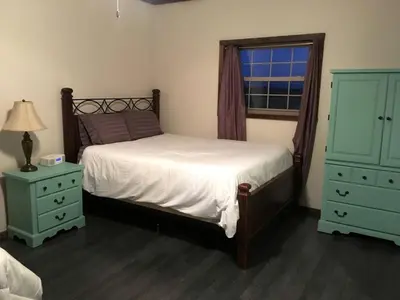 a bedroom with a bed and two dressers and a window at Rustic Cabin in the Countryside near Muskingum River State Park, Ohio in McConnelsville