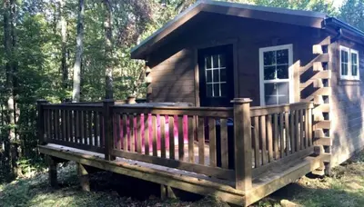 a small cabin with a large deck in the woods at Romantic Log Cabin Accommodation with Private Jacuzzi near Huntington, West Virginia in Genoa