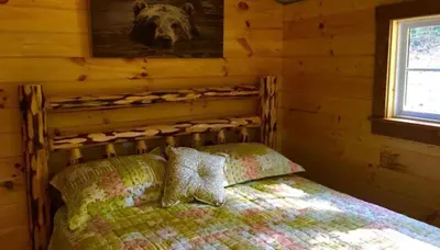 a bedroom with a bed in a log cabin at Romantic Log Cabin Accommodation with Private Jacuzzi near Huntington, West Virginia in Genoa