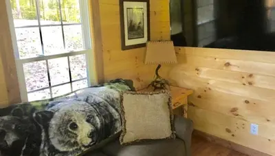 a room with a bed and a table with a lamp at Romantic Log Cabin Accommodation with Private Jacuzzi near Huntington, West Virginia in Genoa
