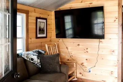 a room with a couch and a tv on a wall at Romantic Log Cabin Accommodation with Private Jacuzzi near Huntington, West Virginia in Genoa