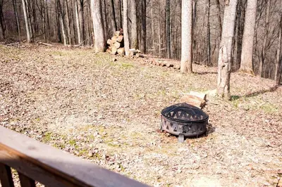 a grill sitting on the ground in the woods at Romantic Log Cabin Accommodation with Private Jacuzzi near Huntington, West Virginia in Genoa