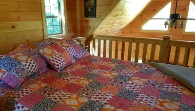 a bedroom with a quilt on a bed in a cabin at Rustic Family-Friendly Accommodation with Jacuzzi near Huntington, West Virginia in Genoa