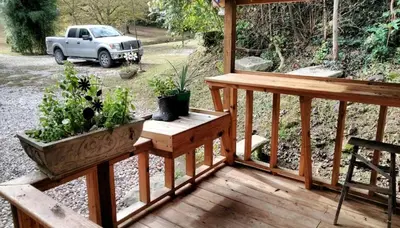 a porch with two potted plants and a truck at Gorgeous Vacation Cabin for Groups with Stylish Interior near Huntington, West Virginia in Genoa