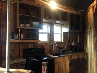 a kitchen with wooden cabinets and a stove and a sink at Unique Rustic Yurt Rental for a Peaceful Retreat near Huntington, West Virginia in Genoa