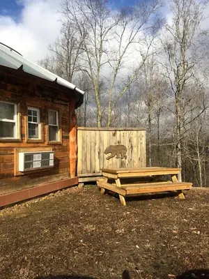 a log cabin with a picnic table next to a fence at Unique Rustic Yurt Rental for a Peaceful Retreat near Huntington, West Virginia in Genoa