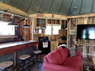 a living room with a red couch and a bar at Unique Rustic Yurt Rental for a Peaceful Retreat near Huntington, West Virginia in Genoa