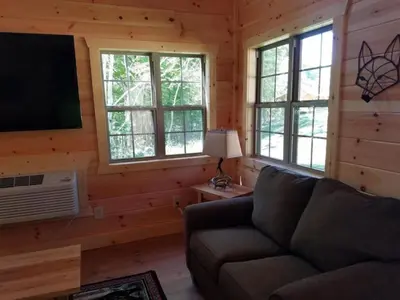 a living room with a couch and a flat screen tv at Cozy Family-Friendly Cabin with Private Outdoor Jacuzzi near Huntington, West Virginia in Genoa