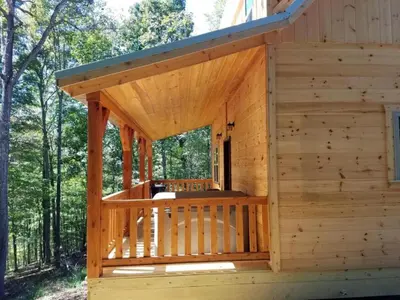a wooden cabin with a deck in the woods at Cozy Family-Friendly Cabin with Private Outdoor Jacuzzi near Huntington, West Virginia in Genoa