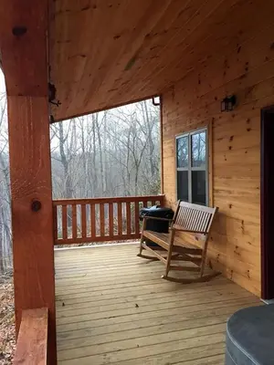 a porch of a wooden cabin with a bench at Cozy Family-Friendly Cabin with Private Outdoor Jacuzzi near Huntington, West Virginia in Genoa