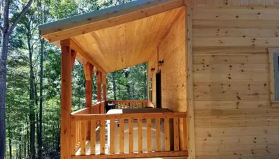 a wooden cabin in the woods with a porch at Cozy Family-Friendly Cabin with Private Outdoor Jacuzzi near Huntington, West Virginia in Genoa