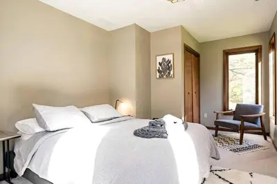 a bedroom with a white bed and a chair at Stunning Home Away From Home in New Albany, Ohio, For Restful Escapes to Nature in New Albany