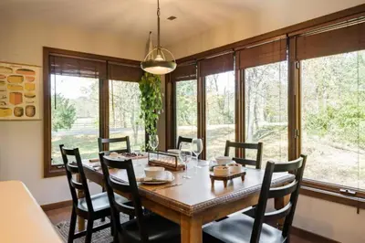 a dining room with a table and chairs and windows at Stunning Home Away From Home in New Albany, Ohio, For Restful Escapes to Nature in New Albany