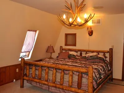 a bedroom with a wooden bed with a antler chandelier at Magnificent A-Frame Cabin Rental in the Trees close to Hocking Hills State Park, Ohio in Laurelville